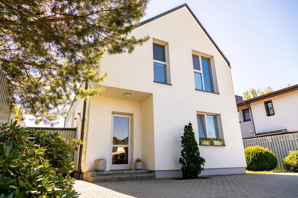 Nowoczesny dom z białą, gładką elewacją wykonaną tynkowaniem maszynowym